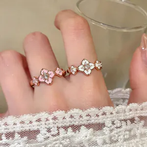 Detail shot of elegant 18K gold plated zircon floral rings with pink and white enamel motifs.