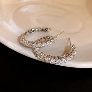 Detailed macro view of elegant silver needle C-shaped hoop earrings with cubic zirconia
