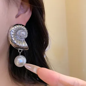Close-up detail of silver nautilus shell drop earrings featuring elegant white pearls