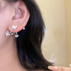 Detailed side view of sparkling silver butterfly stud earrings worn on a model's ear