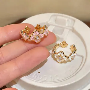 Detailed view of gold-plated rings with enamel flower charms and sparkling zircons.