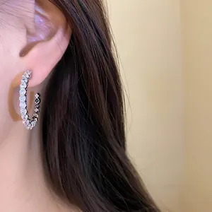 Close-up detail of silver C-shaped hoop earrings featuring brilliant round-cut cubic zirconia