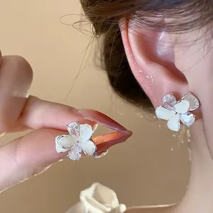 Close-up of elegant flower stud earrings with white petals and sparkling zircon stones