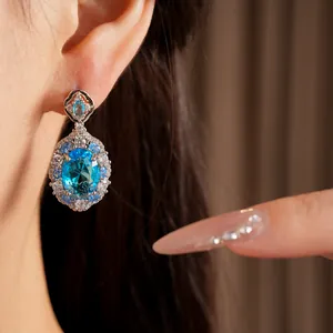 Macro shot of exquisite oval blue zircon drop earrings with shimmering halo detail
