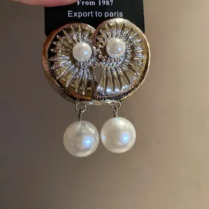 Detail view of vintage-style gold conch shell drop earrings featuring elegant pearls