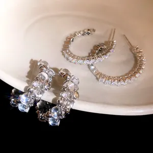 Detailed view of luxury sparkling cubic zirconia C-shaped hoop earrings with silver pins