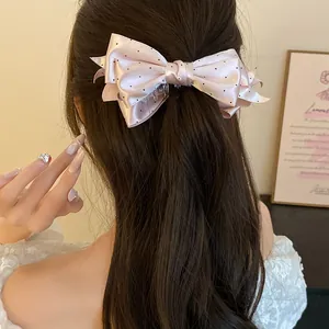 Vue arrière d'une pince banane à nœud en satin rose à pois dans les cheveux longs