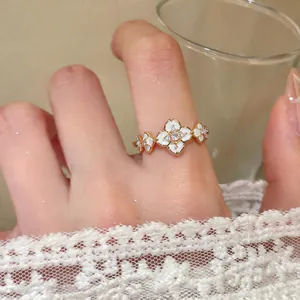 Close-up of elegant 18K gold plated ring with white enamel flowers and sparkly zircons