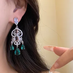 Detailed close-up of silver chandelier earrings with emerald green and pink stones