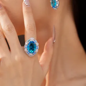 Close-up of an elegant oval blue zircon ring on a finger, part of a luxury jewelry set.