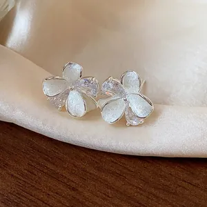 Detailed view of elegant flower stud earrings with sparkling zircon and white enamel.