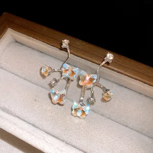 Close-up detail of silver butterfly stud earrings with iridescent rhinestone accents in box