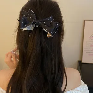 Vue détaillée d'une pince à cheveux en satin noir à pois sur la tête d'un modèle