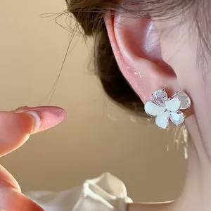 Close-up of elegant flower stud earrings with white enamel and sparkling zircon stones
