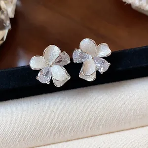 Close-up detail of floral stud earrings featuring sparkling zircons and white enamel finish