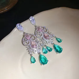 Close-up detail of vintage silver earrings with emerald green and pink waterdrop zircons