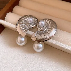 Macro view of shell-shaped silver earrings with pearl drops in a jewelry tray