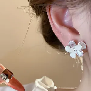 Macro detail of white flower stud earring with shimmering zircon and silver needle