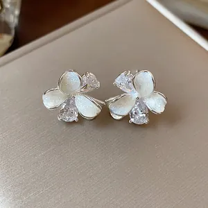 Close-up detail of elegant flower stud earrings with sparkling zircons and enamel petals