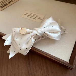 Gros plan sur une pince à cheveux élégante en satin à pois avec breloque dorée