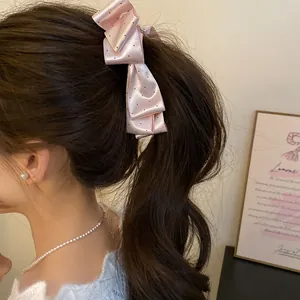 Vue détaillée de la barrette à cheveux nœud en satin rose à pois portée par le modèle