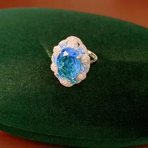 Exquisite oval blue zircon ring with shimmering halo crystals on dark green velvet