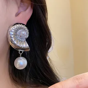 Detailed view of an elegant silver conch earring featuring a lustrous white pearl drop