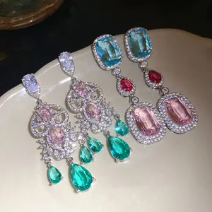 Macro view of sparkly colorful zircon drop earrings on a ceramic plate