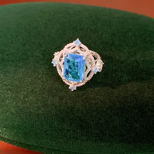 Close-up of luxury ring with rectangular blue zircon on green velvet background