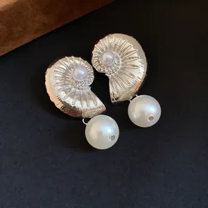 Detailed close-up of silver conch earrings with elegant white pearl drops.