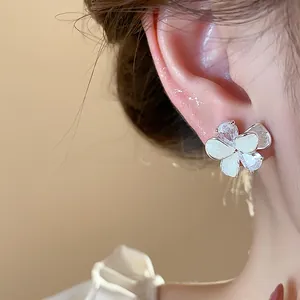 Close-up of sparkling zirconia flower stud earrings with elegant white enamel petals.