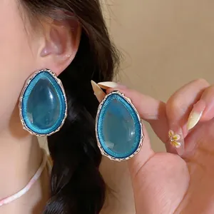 Eleganti orecchini a goccia in resina blu con bordo metallico mostrati indossati