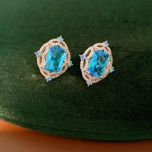 Detailed view of elegant emerald-cut blue zircon earrings featuring a sparkling halo setting