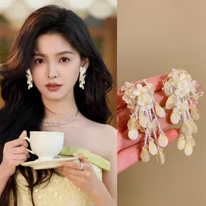 Detailed view of milky yellow floral tassel earrings featuring model try-on and close-up.