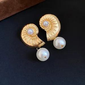 Detailed view of luxurious gold seashell earrings featuring elegant dangling large white pearls