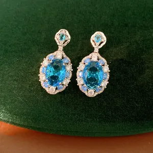 Macro detail of elegant oval blue zircon drop earrings featuring a sparkling halo design