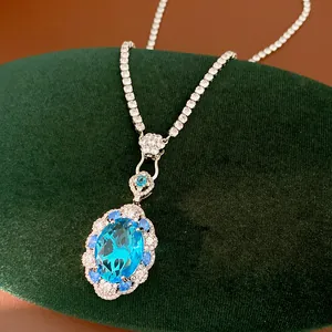 Close-up of luxurious blue oval zircon pendant with tennis chain on green velvet.
