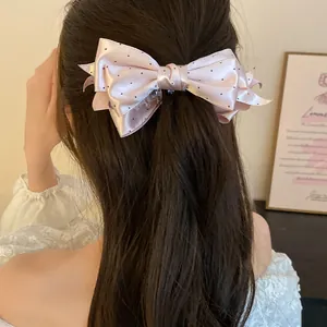 Vue arrière d'un modèle portant une pince à cheveux banane avec un nœud en satin rose