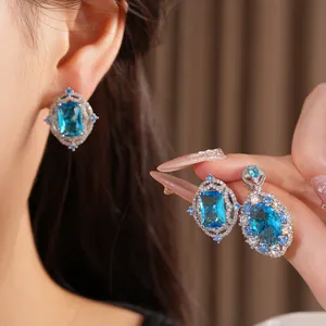 Close-up of elegant blue zircon jewelry set with rectangle earrings and oval pendant.