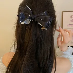Vue arrière d'une femme portant une pince à cheveux nœud en satin noir à pois