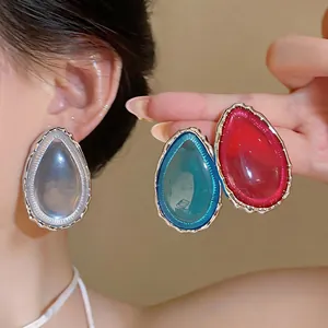 Dettaglio di eleganti orecchini in resina a goccia d'acqua in blu e rosso con cornice argentata
