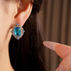 Detailed view of vintage silver stud earring with emerald-cut blue zircon worn by model