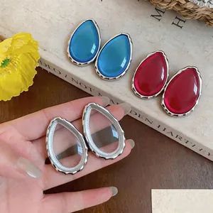 Primo piano di orecchini a goccia in resina colorata nei toni blu, rosso e chiaro.