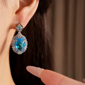 Close-up detail of luxurious blue oval zircon drop earring with sparkling halo stones