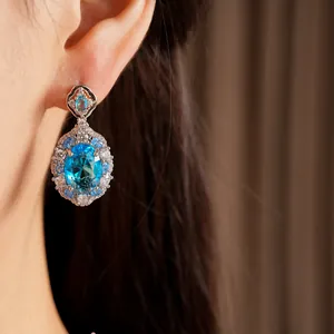 Close-up view of elegant blue zircon oval drop earring worn on ear for luxury look