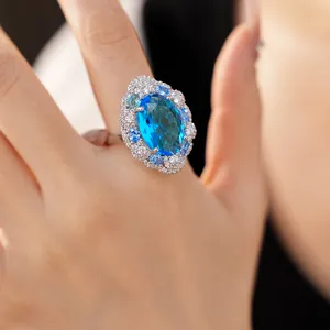 Close-up view of an elegant luxury blue oval zircon ring with crystal halo on hand