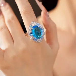Close-up of elegant oval blue cubic zirconia ring with sparkling accent stones on hand