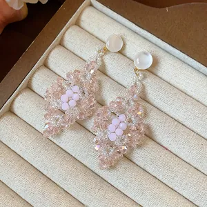 Detalle macro de pendientes de gota de cuentas rosas en forma de rombo en bandeja