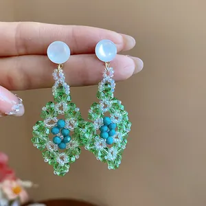 Detalle de pendientes de rombo de cristal verde estilo bosque con cuentas de cristal