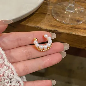 Close-up of a French style double-layered pearl and gold-tone twisted ear cuff on hand